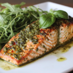 Pesto salmon fillet garnished with basil and lemon wedges.